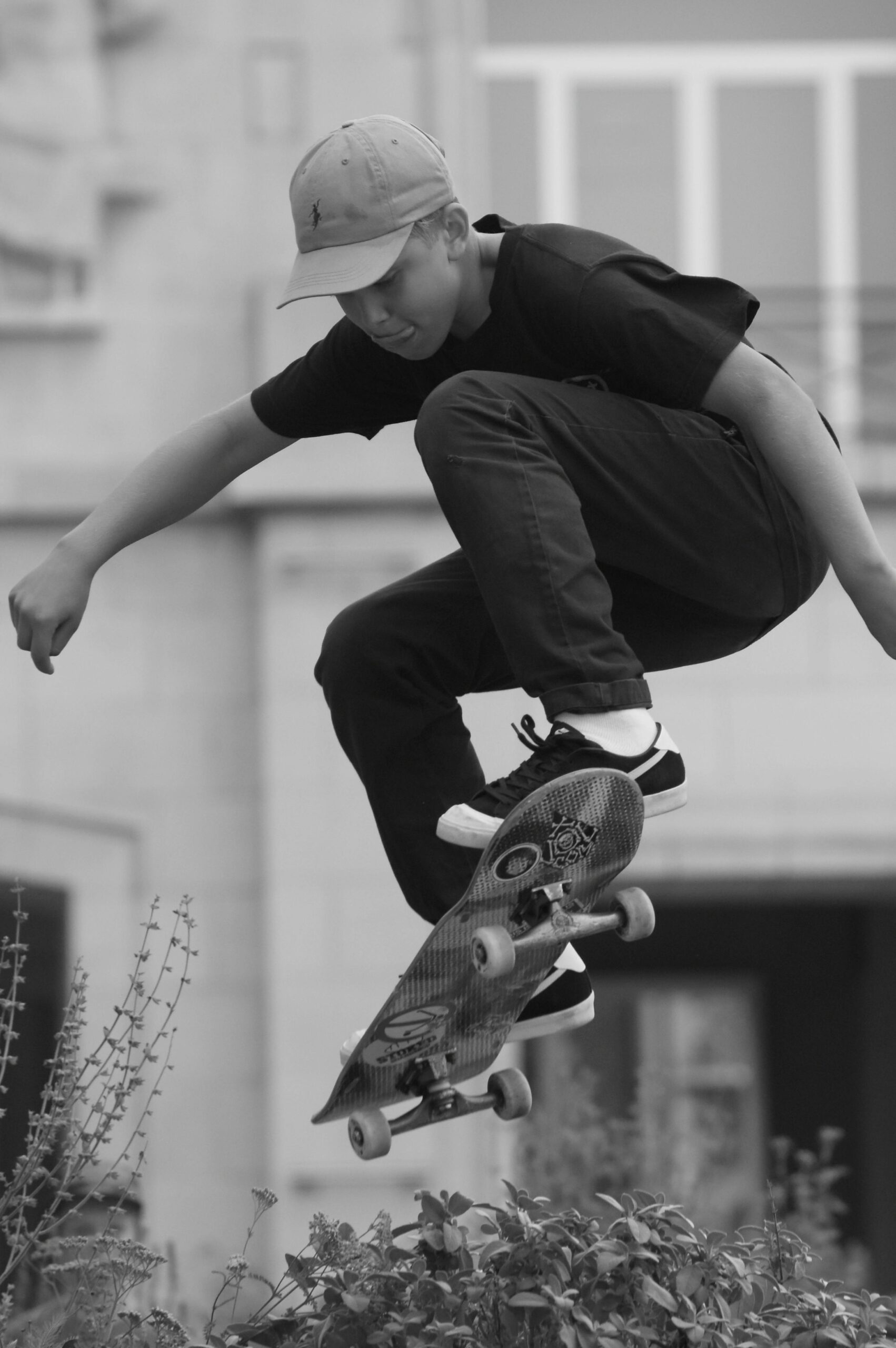 A young male skater in mid-air performing a jump with a skateboard outdoors.