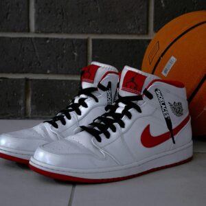 White and red basketball sneakers with an orange basketball on tiled floor.